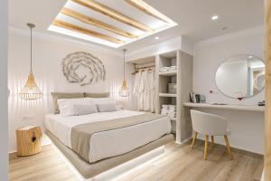 a white bedroom with a bed and a mirror at Villa Adriana Hotel in Agios Prokopios