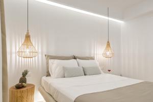 a white bedroom with a bed and two pendant lights at Villa Adriana Hotel in Agios Prokopios