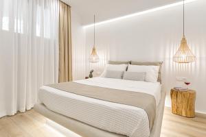 a white bedroom with a large bed and two pendant lights at Villa Adriana Hotel in Agios Prokopios
