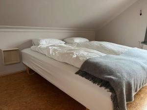Una cama blanca con dos almohadas encima. en Lítið einbýlishús á besta stað. en Vestmannaeyjar