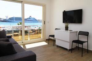 a living room with a couch and a desk with a television at Ufuk Hotel in Cesme