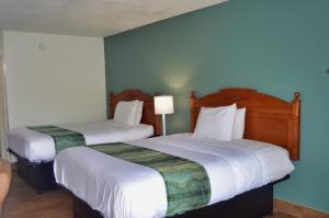 a hotel room with two beds with white sheets at Days Inn by Wyndham Hardeeville Near Hilton Head in Hardeeville