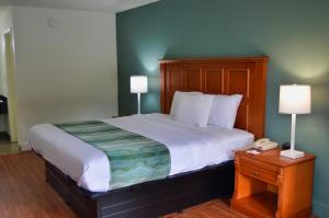 Cama en habitación de hotel con 2 lámparas y teléfono en Days Inn by Wyndham Hardeeville Near Hilton Head, en Hardeeville