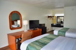 a hotel room with two beds and a desk with a television at Days Inn by Wyndham Hardeeville Near Hilton Head in Hardeeville