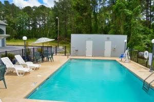 a swimming pool with chairs and a table and umbrella at Days Inn by Wyndham Hardeeville Near Hilton Head in Hardeeville