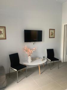 een woonkamer met een tafel en twee stoelen en een televisie bij Georgia's house in Ária