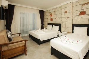 um quarto de hotel com duas camas e uma cadeira em Lebedos Apart Hotel em Gumuldur