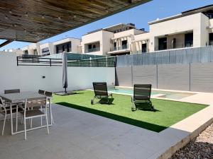 a patio with a table and chairs and grass at Agradable chalet con piscina privada cerca de Madrid in Madrid