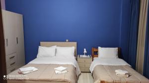 a blue room with two beds with towels on them at Porto Sabatiki in Sampatiki