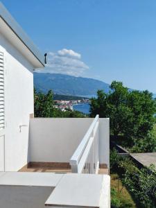 a white house with a white railing and a stair case at Apartment Boras in Senj