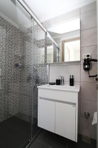 a bathroom with a white sink and a shower at Ufuk Hotel in Cesme