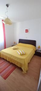 a bedroom with a yellow bed with two towels on it at Apartments Buzleta in Fažana