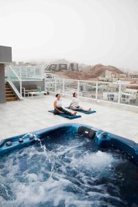 twee mensen zitten aan de rand van een zwembad bij Spa Eilat Mountain Lodge in Eilat