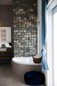 y baño con bañera y pared de ladrillo. en Spa Eilat Mountain Lodge, en Eilat