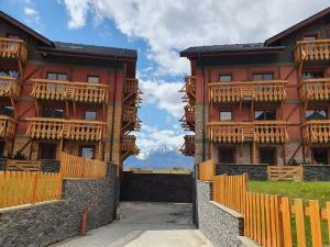 a red building with wooden balconies and a fence at Comfortable One-Bedroom Apartment TATRAGOLF in Veľká Lomnica