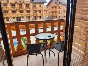 a balcony with a table and chairs and a view of a city at Comfortable One-Bedroom Apartment TATRAGOLF in Veľká Lomnica