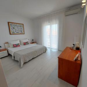a white bedroom with a bed and a wooden floor at Guest House Mediterranean in Hvar