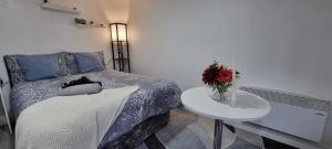 um quarto com uma cama e uma mesa com um vaso de flores em Charming, cosy hideaway with free WiFi, parking em Roundhay