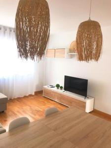 ein Wohnzimmer mit einem TV und einem Tisch mit Stühlen in der Unterkunft Apartamento con piscina Navarrete in Navarrete