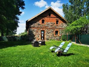 an old stone building with two chairs in front of it at Mazurski Ogród - dom z ogrodem, kominkiem i wiatą biesiadną in Wydminy