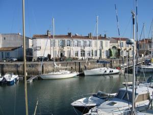 un gruppo di imbarcazioni ormeggiate in un porto con edifici di ILE DE RE, LA DANAE avec VELOS, WIFI, COIN CUISINE, LINGE, PARKING gratuit a Saint-Martin-de-Ré