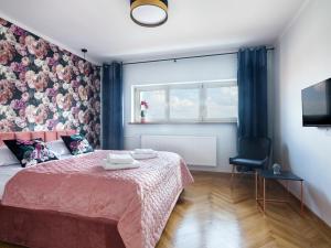 a bedroom with a pink bed and a window at CracWoW City Center Apartment in Krakow