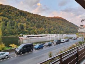 a train traveling down a highway next to a river with cars at Römerstube Apartments & rooms in Ediger-Eller