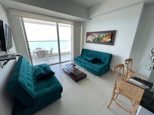 sala de estar con 2 sofás verdes y balcón en Playa Cartagena Apartments en Cartagena de Indias