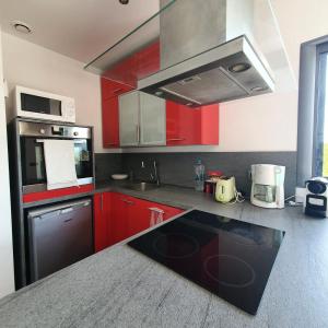 kuchnia z czerwonymi szafkami i czarnym urządzeniem w obiekcie Chez J, appartement à l'étage, T3 w mieście Lecci