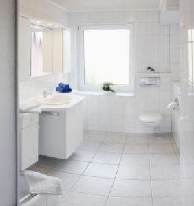 a white bathroom with a sink and a toilet at Haus Tanneck Whg 7 in Kellenhusen