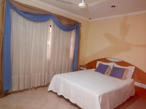 a bedroom with a bed with blue curtains and a window at Quinta Jardin in San Lorenzo de la Frontera