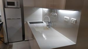 eine weiße Küche mit Spüle und Kühlschrank in der Unterkunft On the sea in Aschkelon