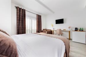a bedroom with a white bed and a television at Boutique Residence Arion in Rovinj