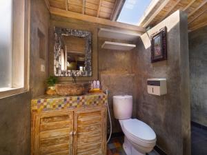 a bathroom with a toilet and a sink and a mirror at Wisnu Lumbung Uluwatu in Uluwatu