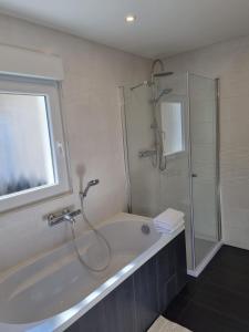 La salle de bains est pourvue d'une douche et d'une baignoire. dans l'établissement Ferienhaus an der Saar, à Merzig