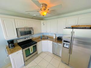 a kitchen with white cabinets and a stainless steel refrigerator at #1203 Lovers Key Beach Club in Fort Myers Beach