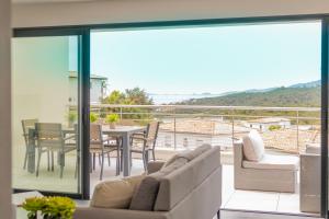 a balcony with a couch and a table and chairs at Coucher de soleil in Porticcio