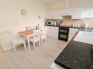 una cucina con un tavolo in legno e mobili bianchi di Robin House a Lucker Altre 13 foto
