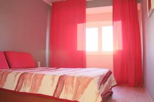 a bedroom with a bed with red curtains and a window at Сomfortable apartments and free garage parking in Porto