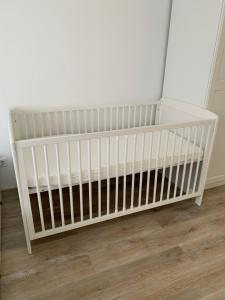a white crib in a room with a wooden floor at Noorhus - Kurzurlaub an der Ostsee in Maasholm