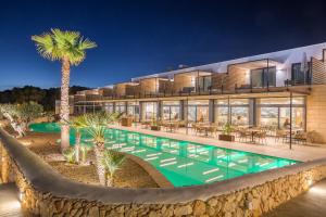 an exterior view of a building with a pool and a palm tree at Barceló Nura in Sant Lluis