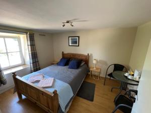 een slaapkamer met een bed met blauwe kussens en een tafel bij Le Gite De Malchamps in Spa