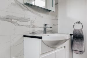 a white bathroom with a sink and a mirror at Private Two Bedroom Residence in Southbourne - Private Parking - Off the High Street - Minutes Away from the Beach in Bournemouth +30 photos
