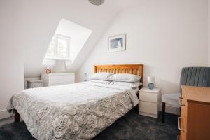 a white bedroom with a bed and a chair at Private Two Bedroom Residence in Southbourne - Private Parking - Off the High Street - Minutes Away from the Beach in Bournemouth