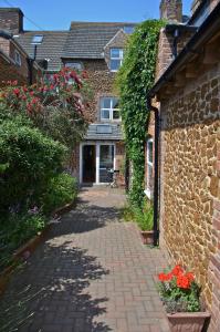 una pasarela de ladrillo que conduce a un edificio con flores en Honeycomb House Apartments, en Hunstanton