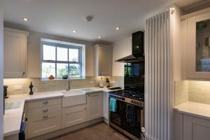 a kitchen with white cabinets and a stove top oven at Ayr Farmhouse in St Ives