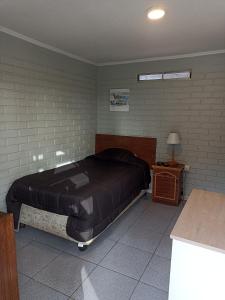 ein Schlafzimmer mit einem Bett mit einer schwarzen Tagesdecke und einem Tisch in der Unterkunft Alojamientos JV HABITACIONES in Nogales