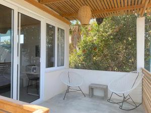 a porch with two chairs and a table and windows at Perro Surfero Hotel in Todos Santos