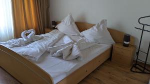 Una cama con sábanas blancas y almohadas. en Casa Silvia, en Eforie Nord
