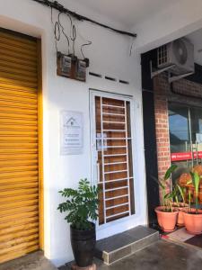 une porte d'entrée d'un bâtiment avec une usine de pot dans l'établissement BenBahrains Homestay - PB - ISLAMIC COMPLIANCE ONLY, à Masjid Tanah